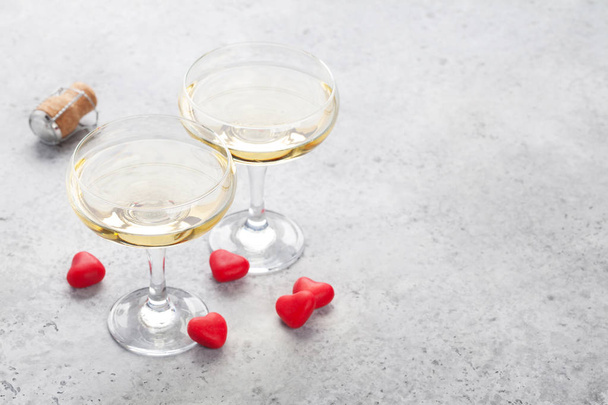 Открытки на день Святого Валентина с шампанским и конфетными сердечками на каменном фоне
 - Фото, изображение