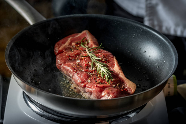 Close view of fresh beefsteak cooking with spices and rosemary twig on pan - Fotografie, Obrázek