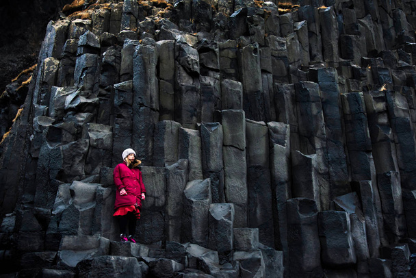 Női utas a sziklák, a fekete homokos Reynisfjara strandtól, Izland - Fotó, kép