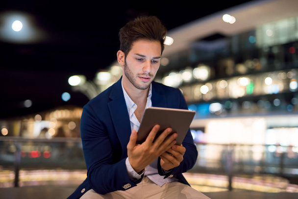 Portrait of man using his tablet in a city at night - Photo, image