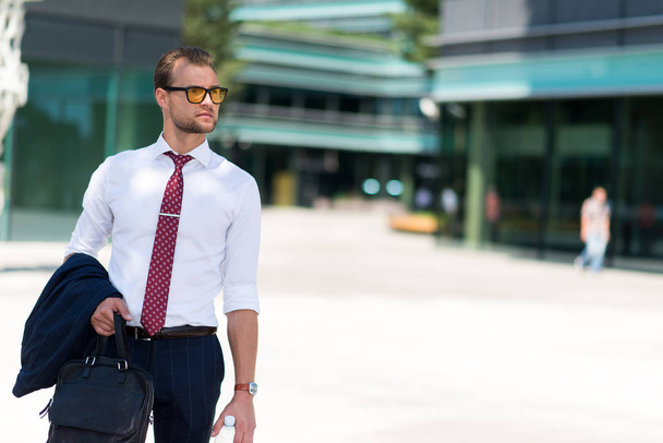 Portrait of a young handsome businessman walking in a city - Fotó, kép
