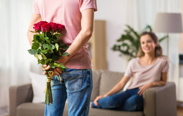woman and man with bunch of roses behind his back - Photo, image