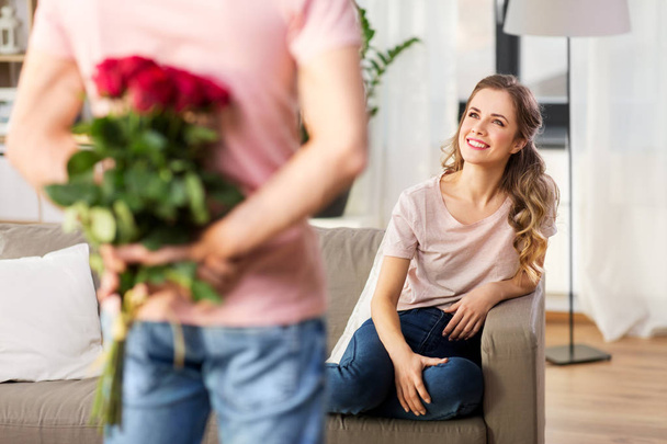 woman looking at man with bunch of flowers at home - Foto, immagini