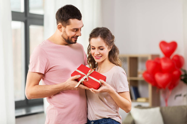 couple with gift box on valentines day at home - Фото, изображение