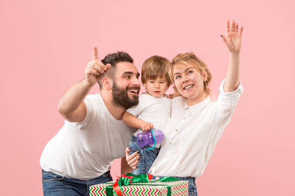 happy family with kid together and smiling at camera isolated on pink - Foto, Imagen