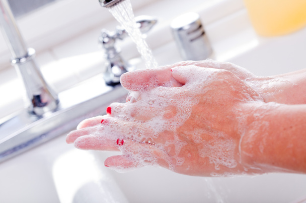 Женщина, моющая руки в раковине на кухне
. - Фото, изображение