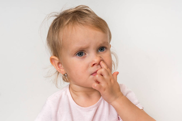 Baby girl is picking her nose with finger inside - hygiene concept - Photo, Image
