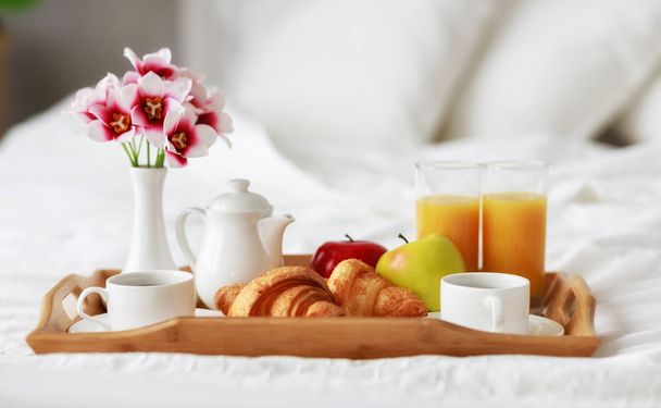 desayuno en cama de café, croissants, zumo de naranja y fruta en una bandeja
 - Foto, Imagen