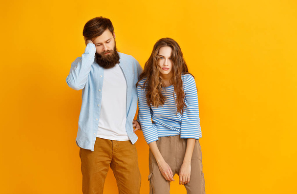 couple of young emotional tired people man and woman on yellow backgroun - 写真・画像