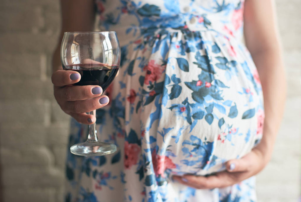 Toekomstige moeder omarmen buik en drinken van schadelijk alcohol terwijl verwachten baby - Foto, afbeelding