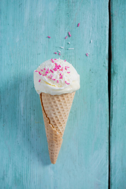 single vanilla ice cream in waffle scone on turquoise surface - Foto, imagen
