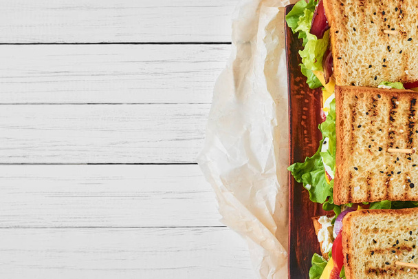 Три бутерброди з шинкою, салатом і свіжими овочами на білому тлі, вид зверху з місцем для тексту
 - Фото, зображення