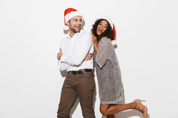 Cheerful young smartly dressed couple celebrating New Year isolated over white background - Valokuva, kuva