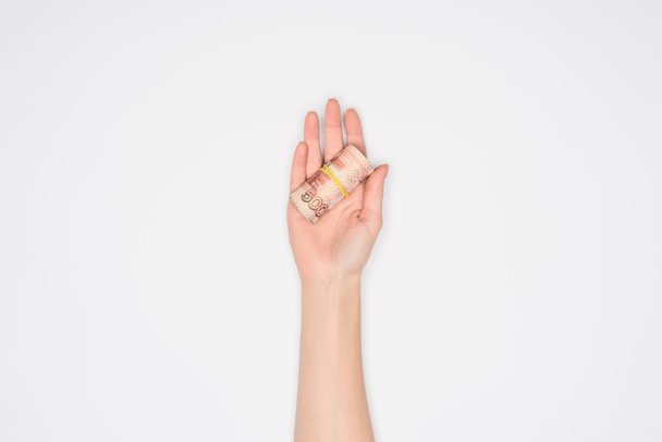 visão parcial da mulher segurando rolo de dinheiro em palma aberta isolada em cinza
 - Foto, Imagem