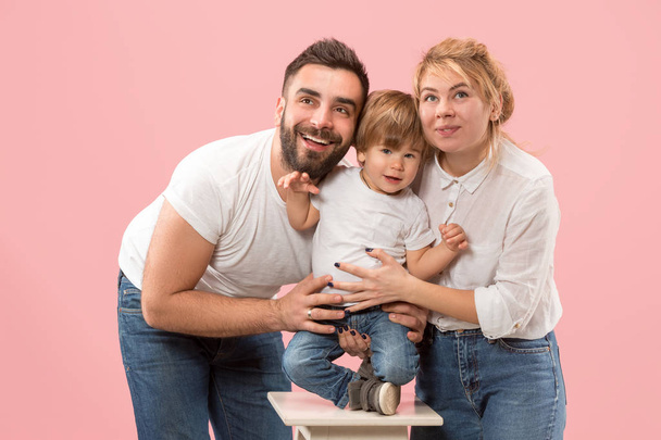 happy family with kid together and smiling at camera isolated on pink - Foto, afbeelding