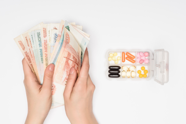 bijgesneden beeld van vrouw tellen Russische roebel in de buurt van pillen in vak geïsoleerd op grijs - Foto, afbeelding