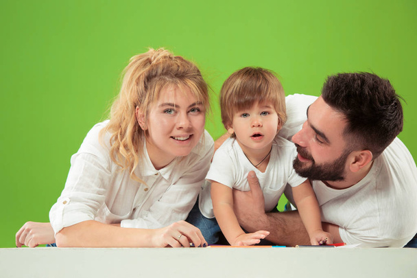 família feliz com criança juntos e sorrindo para a câmera isolada no verde
 - Foto, Imagem