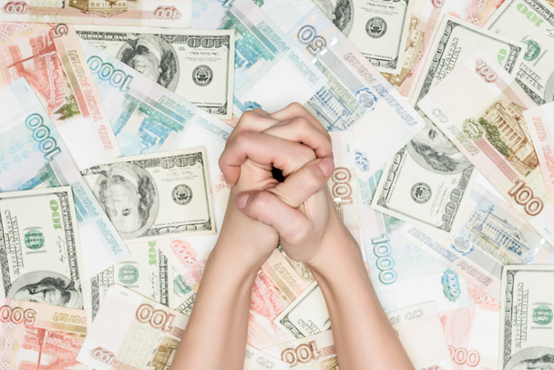 обрезанный вид женских сжатых рук на денежном фоне
 - Фото, изображение