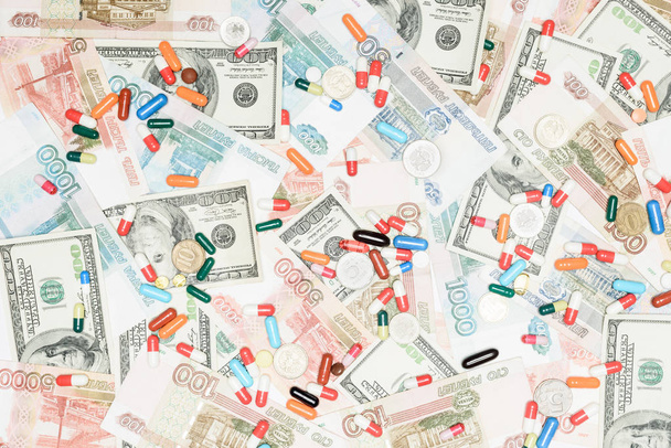 bovenaanzicht van veelkleurige pillen en munten op roebels en dollars achtergrond - Foto, afbeelding