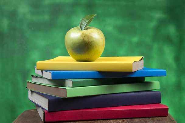 Zelené jablko ovoce na hromádku knih, na zadní straně školní třídy - Fotografie, Obrázek