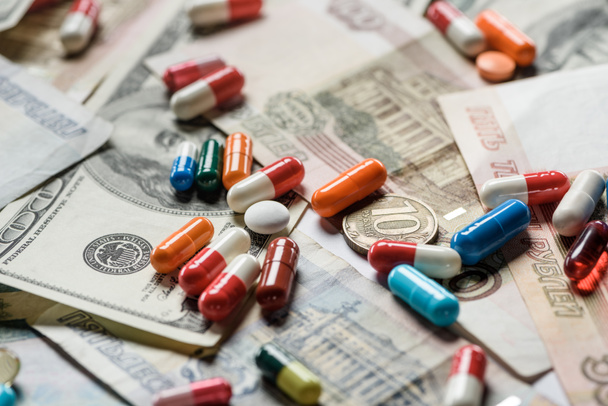 Close up van kleurrijke pillen en munten op geld achtergrond - Foto, afbeelding