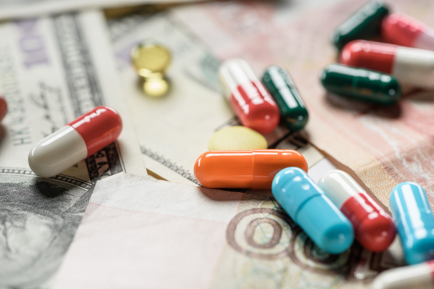 selective focus of bright pills on banknotes background - Foto, afbeelding