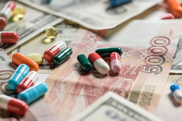 close up of multicolored pills on money background - Фото, зображення