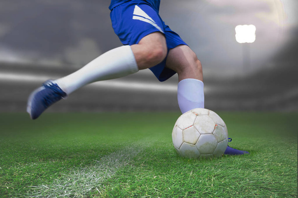 Football player kicking ball against close-up of soccer field - Photo, image