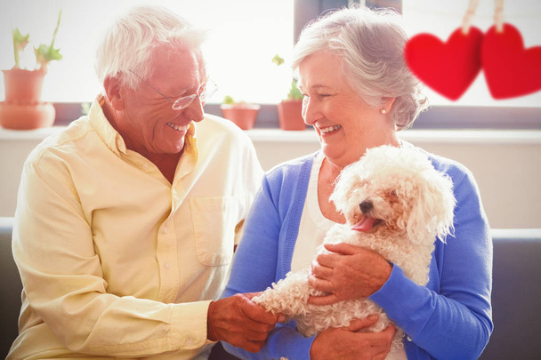 Hearts hanging on a line against senior couple holding a dog - Фото, изображение