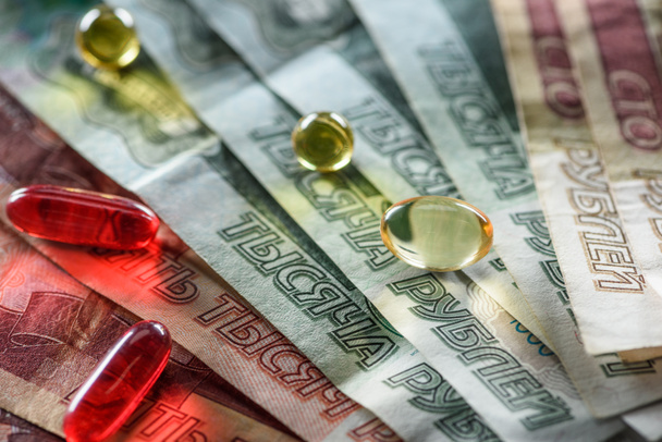 close up de pílulas redondas ovais e amarelas vermelhas no fundo em dinheiro
 - Foto, Imagem