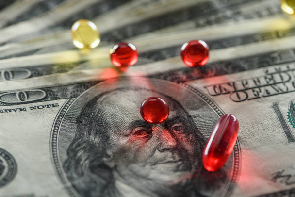 close up de pílulas ovais e redondas brilhantes em dólares de fundo
 - Foto, Imagem
