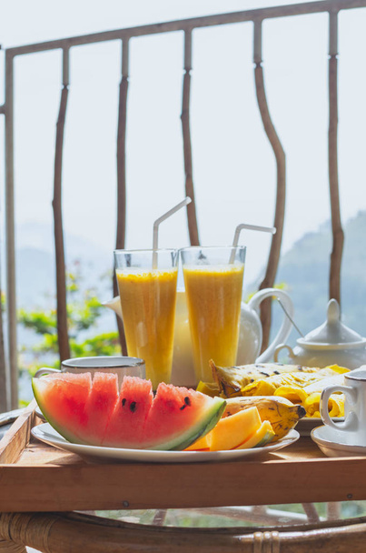 Krásně podává snídani na terase nebo balkonu, Hotelový pokoj, resort - čerstvé meloun, mango, banán, smoothie, palačinky, konvice, šálky, ratanové křeslo - Fotografie, Obrázek