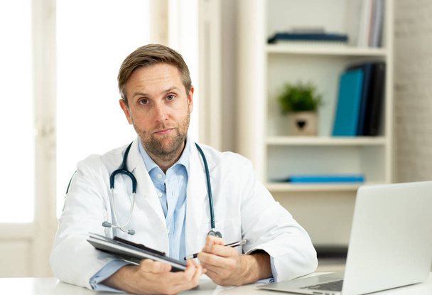 Portrait of handsome doctor working on laptop in hospital clinic office room with natural looking in Health care successful professionals and medical Insurance advertisement concept. - Photo, image