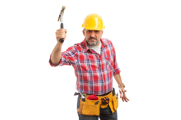 Constructor con expresión enojada amenazando con golpear con un martillo aislado en el fondo del estudio blanco
 - Foto, Imagen