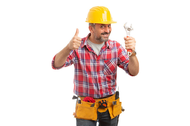 Uśmiechnięty mężczyzna konstruktora trzymając klucz i kciuk w górę jak gest na białym tle - Zdjęcie, obraz