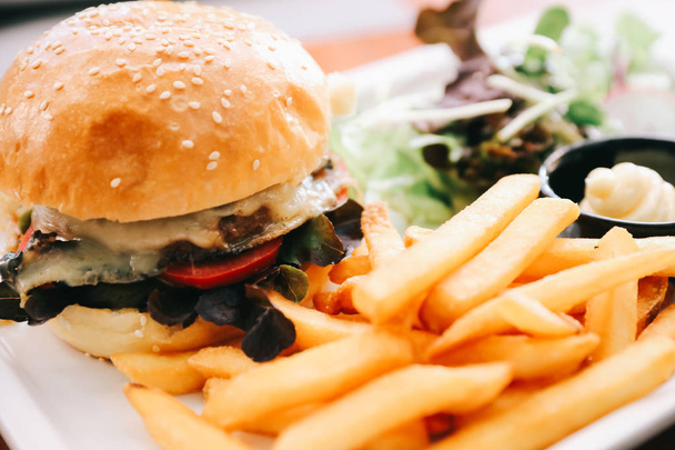 Говяжий гамбургер с картошкой фри и салатом на деревянном фоне
 - Фото, изображение