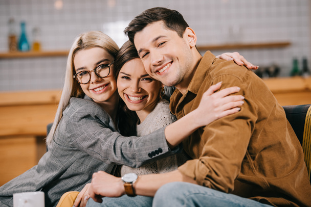 smiling woman in glasses hugging friends in cafe  - Photo, Image