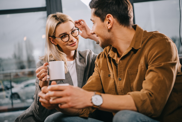 attraente donna in occhiali flirtare con l'uomo mentre tenendo tazza
 - Foto, immagini