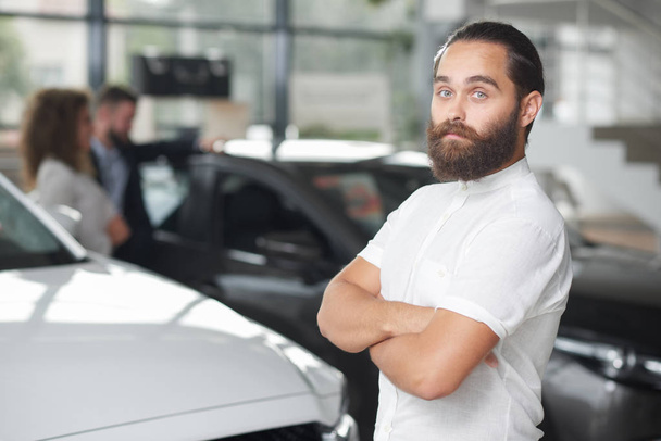 Brutal man posing in car dealership. - Фото, зображення