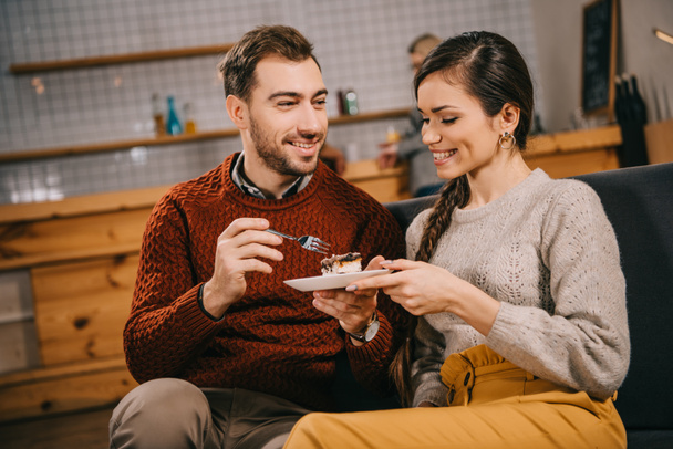 happy man looking at attractive woman with cake in cafe - Photo, Image
