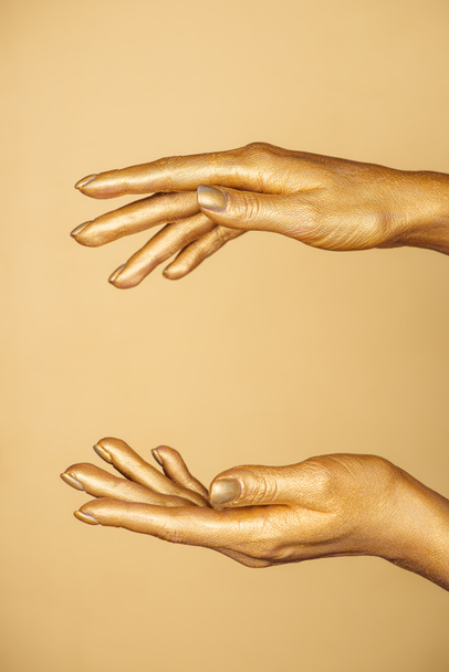 vista recortada de manos pintadas femeninas aisladas en oro
 - Foto, Imagen