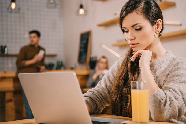 selectieve aandacht van dromerige vrouw met laptop in café - Foto, afbeelding