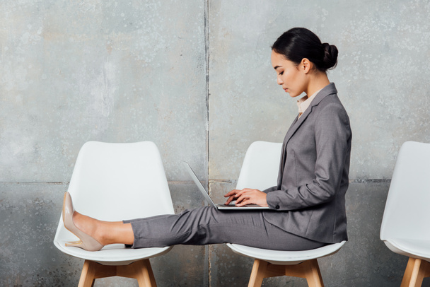 asiatique femme d'affaires en tenue formelle assis sur des chaises et en utilisant ordinateur portable dans salle d'attente
 - Photo, image