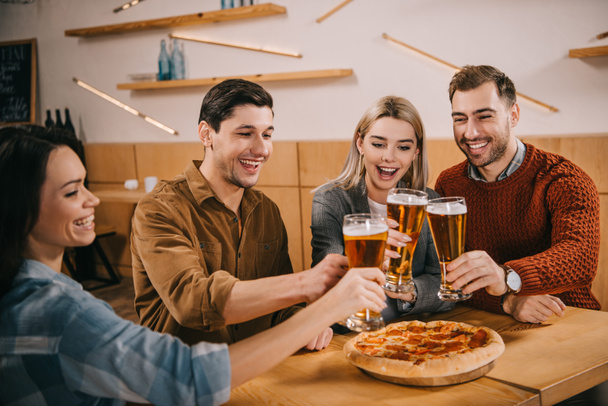 feliz grupo de amigos tintineo cerveza cerca de la pizza en el bar
 - Foto, Imagen