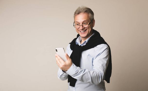 Счастливый старший бизнесмен читает новости на смартфоне
 - Фото, изображение