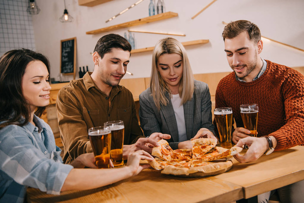 amigos tomando trozos de sabrosa pizza en el bar
 - Foto, imagen