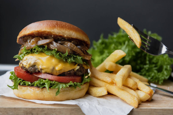 rundvlees hamburger en friet op tafel met zwarte achtergrond. - Foto, afbeelding