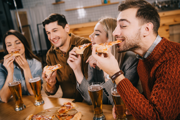 Selektiver Fokus glücklicher Freunde beim Pizza essen in der Bar - Foto, Bild