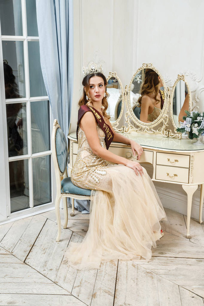 Portrait of beauty brunette model in beige dress sitting at decorated luxury interior  - Foto, Imagem