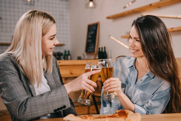 beautiful women smiling while toasting glasses of beer  - Foto, Imagem
